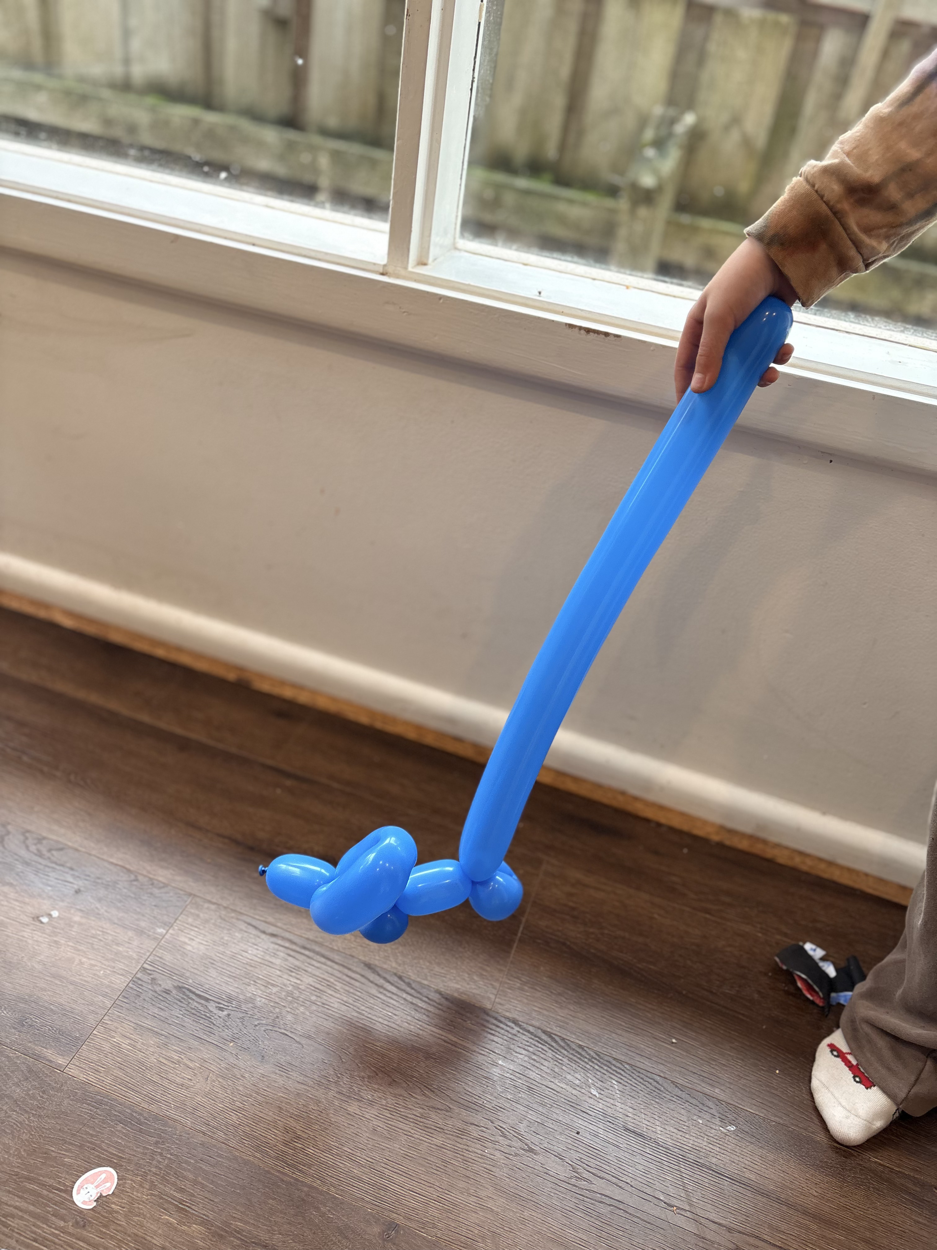 A child holding a tall blue balloon sword with a balloon dog at the tip
